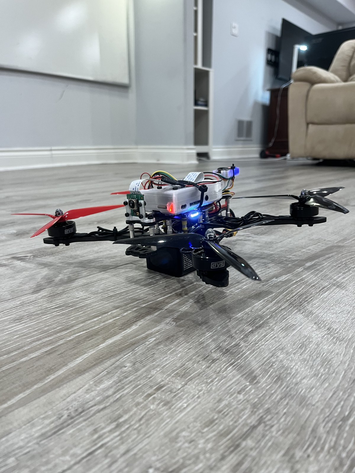 The quadcopter from the side, showing the camera on its front mount and the flight-controller stack.