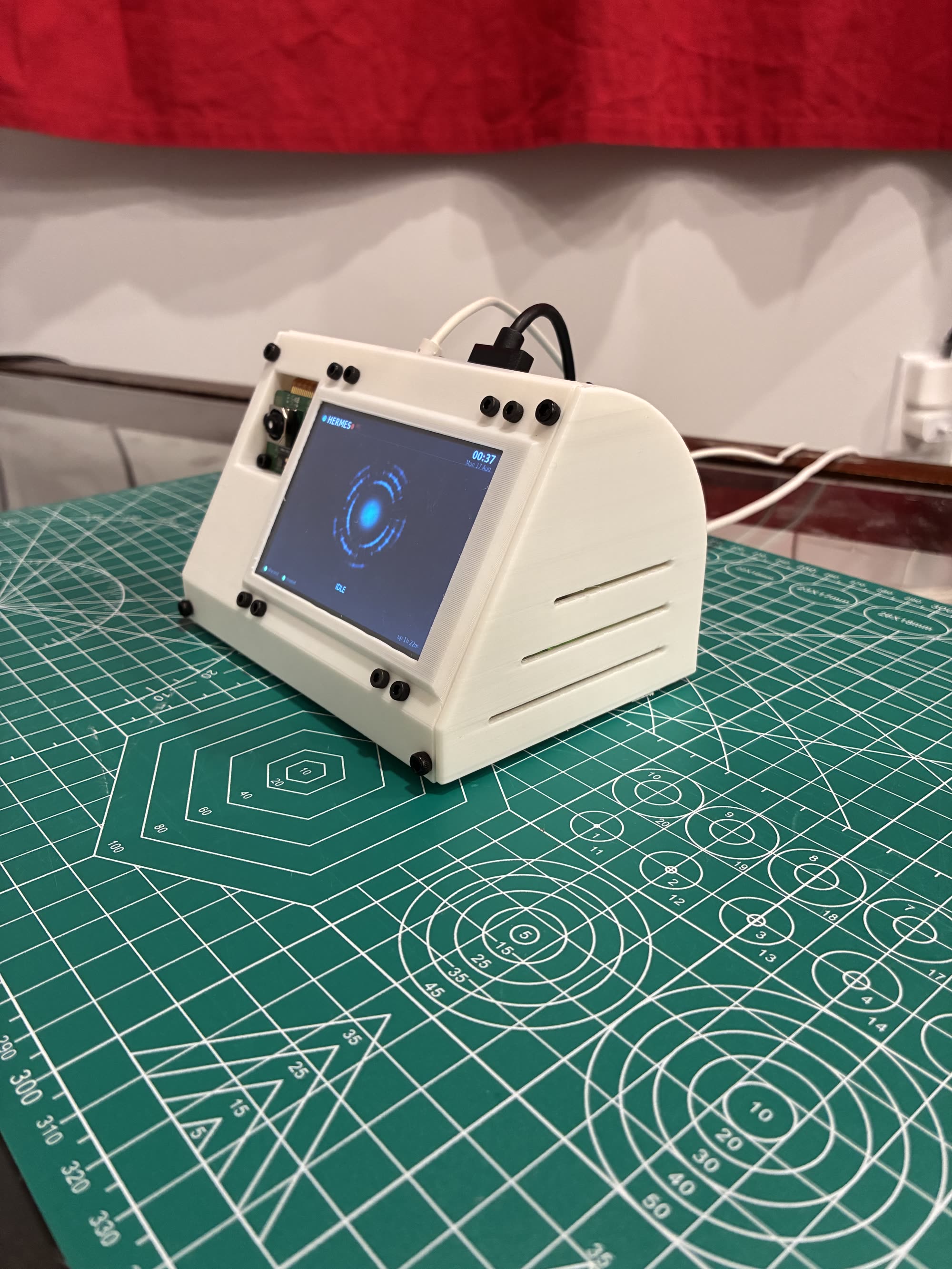 The Hermes Pi from the opposite three-quarter angle, showing the curved rear shell and the cable routing.